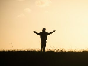 Shadow of person holding arms out at dawn showing gratitude